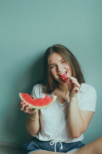 A happy woman eating a slice of watermelon.
